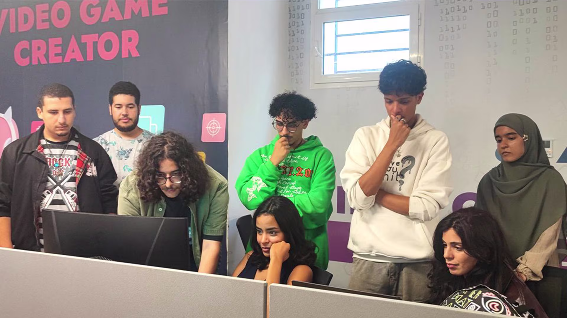 Game jam team reviewing their prototype around a laptop